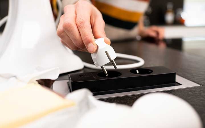 Hand die Stecker in Steckdose steckt.