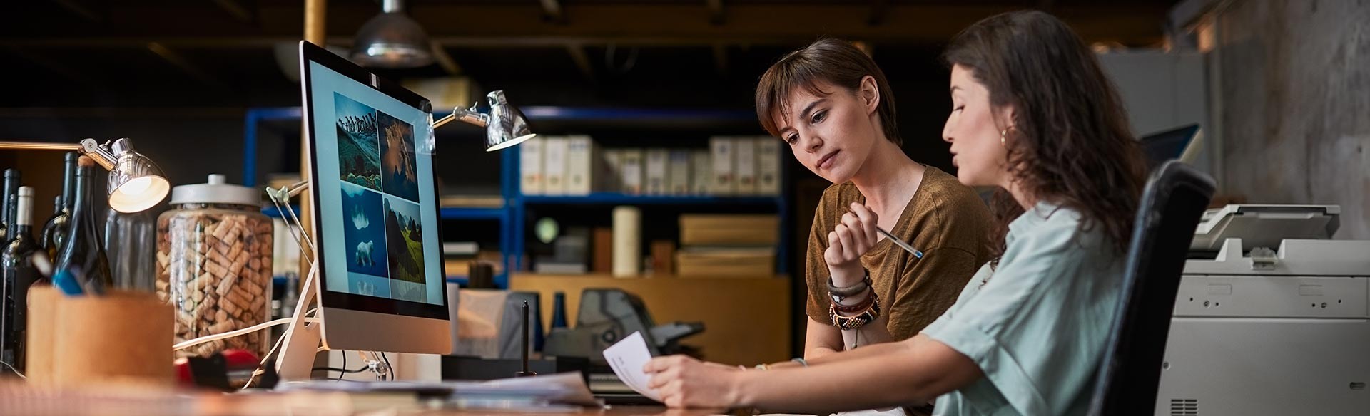 Zwei Frauen besprechen Dokumente vor einem Computer.