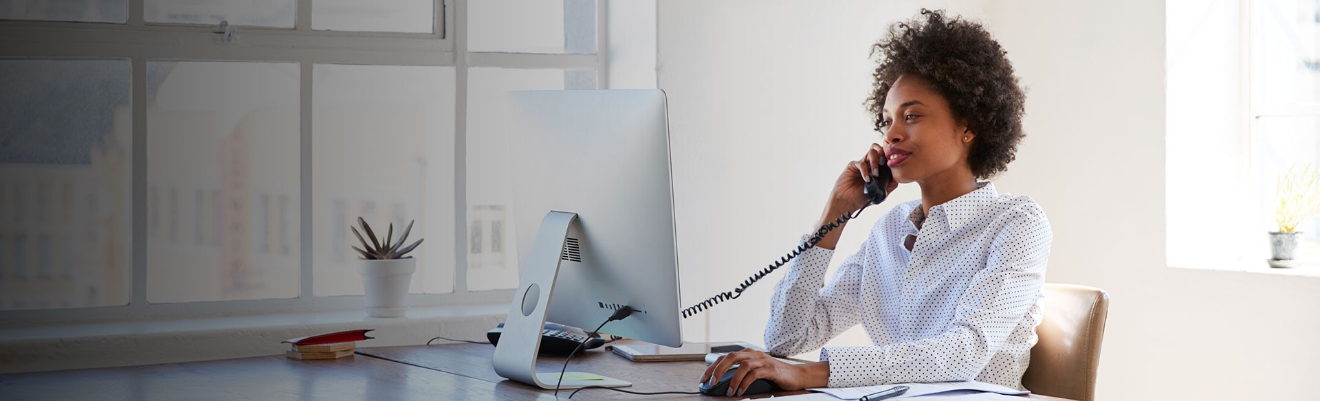 Frau telefoniert am Computer im Büro.