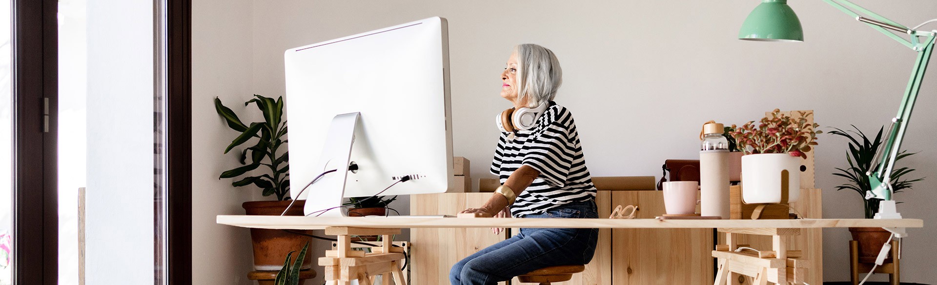 Frau arbeitet an Computer, Kopfhörer um Hals.