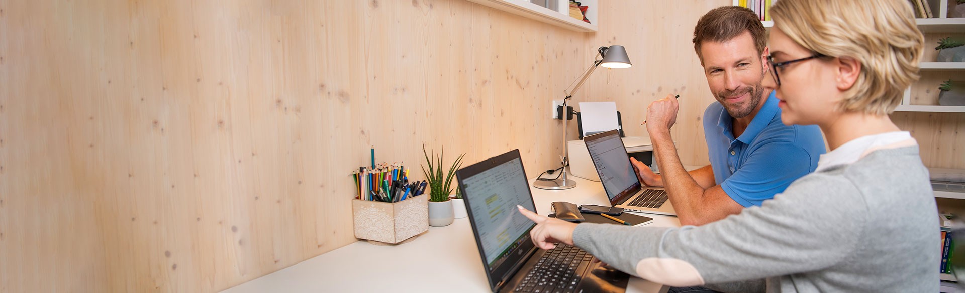 Zwei Personen arbeiten gemeinsam an Laptops.