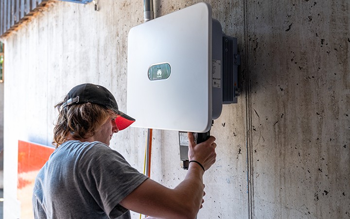 Techniker installiert Wallbox an Betonwand.