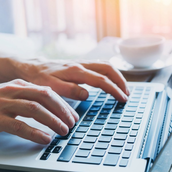 Hände tippen auf Laptop-Tastatur.
