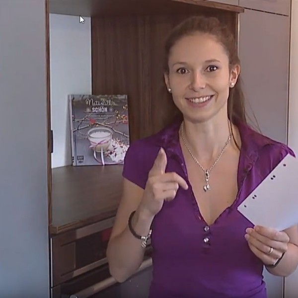 Frau mit lila Shirt und einem Blatt Papier.