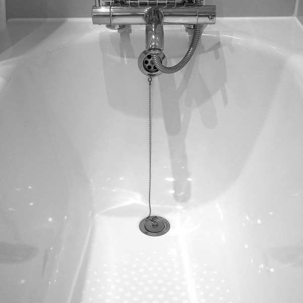 Badewanne mit Armatur und Abflusszugkette.