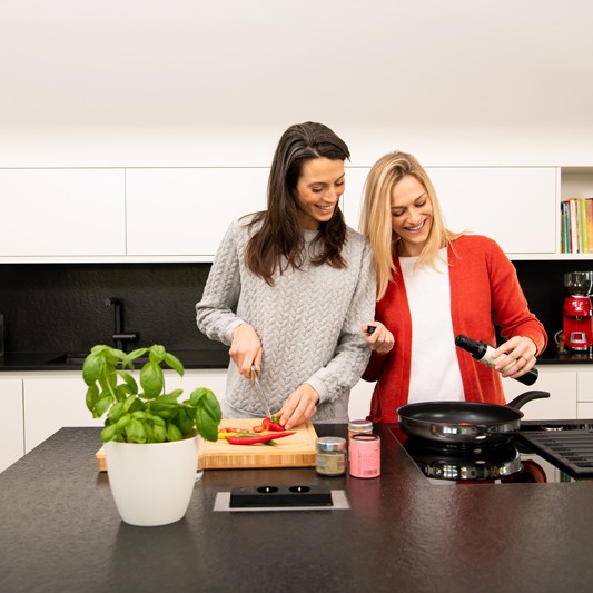Zwei Frauen kochen gemeinsam in moderner Küche.