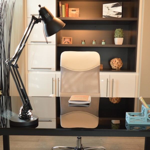 Schreibtisch mit Bürostuhl, Schreibtischlampe und Bücherregal.