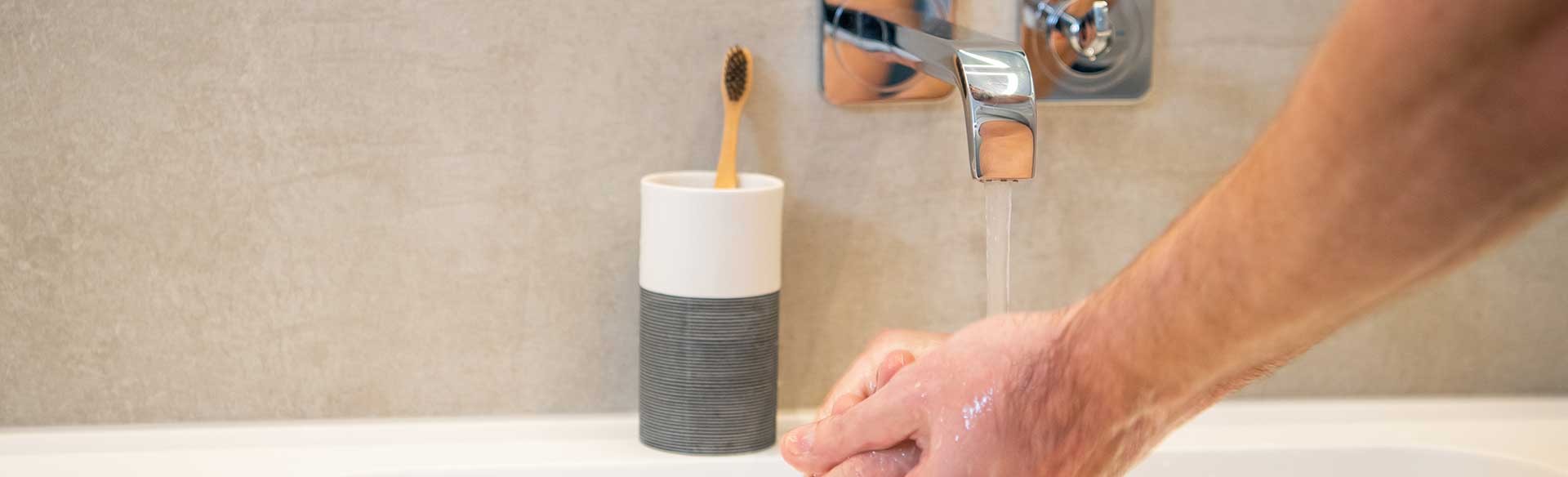 Hände waschen unter fließendem Wasser am Waschbecken.
