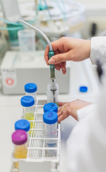 Labormitarbeiterin entnimmt Probe aus Reagenzglas.