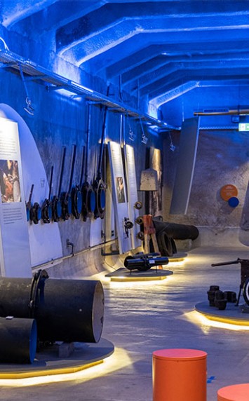 Museumsausstellung: Wasserrohre und historische Wassertechnik in blau beleuchtetem Raum.